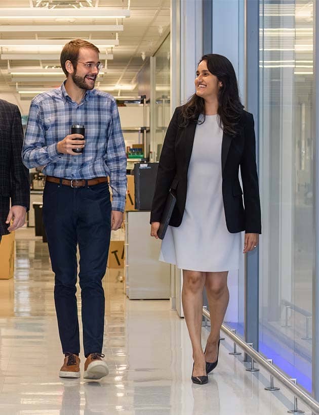 Four colleagues smiling and walking down a hallway.