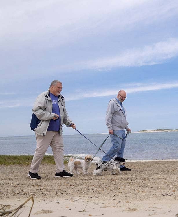 Barry and his husband Randy walking their dogs on the beach.